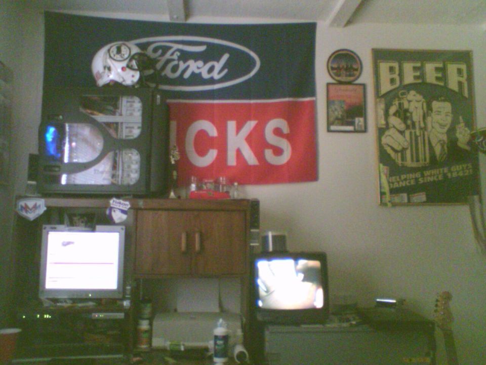 Ford logo flag, 'BEER' poster, and a computer setup with multiple screens