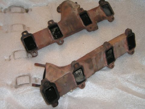 1967 Ford Galaxie - Two used exhaust manifolds, likely from a V8 engine, are shown on a white padded surface.