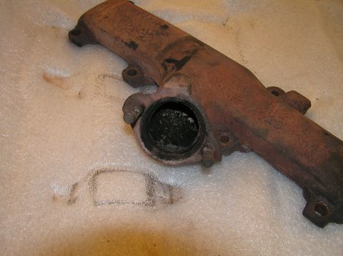 1967 Ford Galaxie - A close-up view of a heavily rusted exhaust manifold, showing significant carbon deposits within the exhaust port.