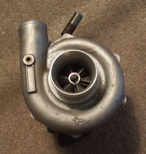 1995 Ford Probe - A turbocharger part is shown against a carpeted surface.