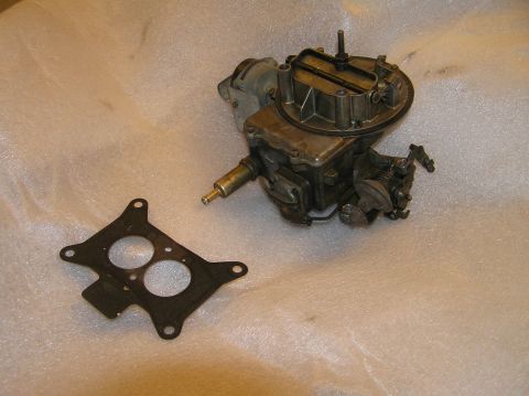 1967 Ford Galaxie - A carburetor and its gasket are displayed on a white, textured surface.
