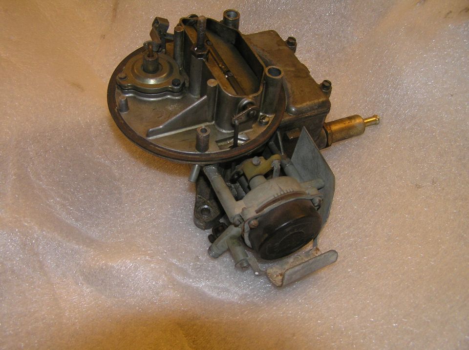 Old automotive carburetor with brass fuel inlet and linkage on white plastic