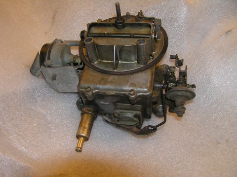 1967 Ford Galaxie - A metal carburetor with brass fittings and a black air horn is shown against a white, textured background.
