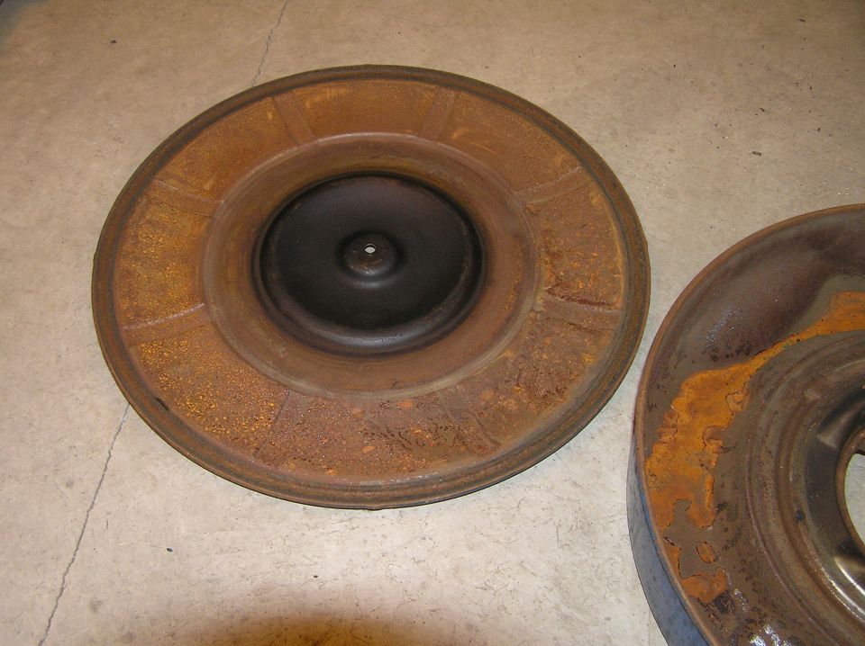 Rusty steel wheel or brake drum on concrete floor, second one at right