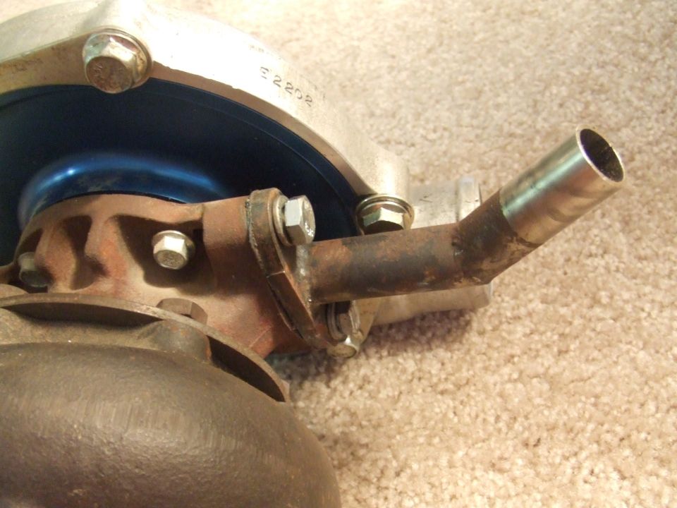 Turbocharger on carpet showing rusty turbine housing, blue plate and oil drain tube