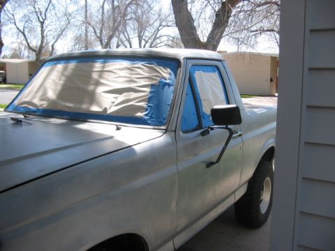 1991 Ford Bronco - A 1991 Ford Bronco is prepped for painting, with its windows covered by tape and drop cloths.