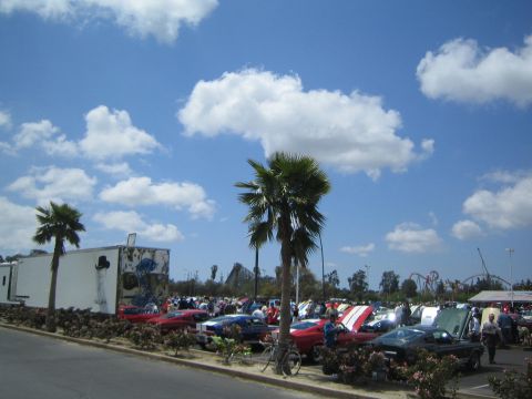 1968 Ford Mustang - A variety of classic cars, including a 1968 Ford Mustang, are displayed at an outdoor car show under a partly cloudy sky.