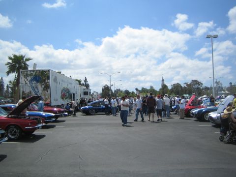 1968 Ford Mustang - A gathering of classic cars and enthusiasts at an outdoor event under a partly cloudy sky.