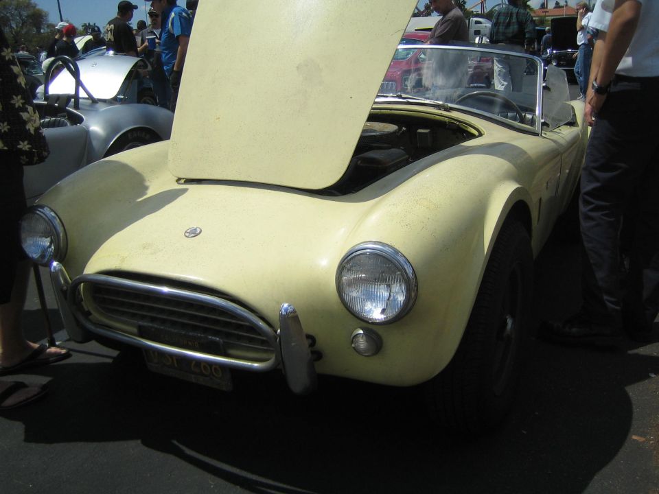 Yellow convertible sports car with hood open, parked next to a silver car
