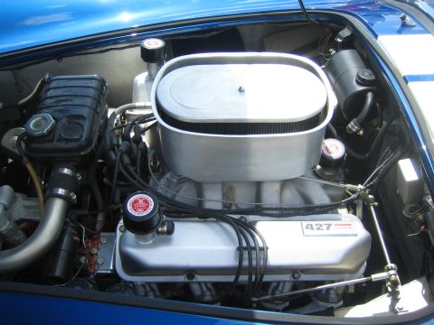 1968 Ford Mustang - Close-up of a powerful engine, identified by its 427 Cobra valve covers and prominent oval air cleaner, housed within a blue vehicle.