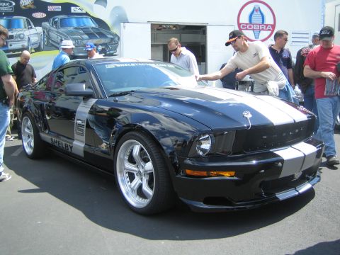 1968 Ford Mustang - A black Shelby Mustang is displayed with people around it at an outdoor event.