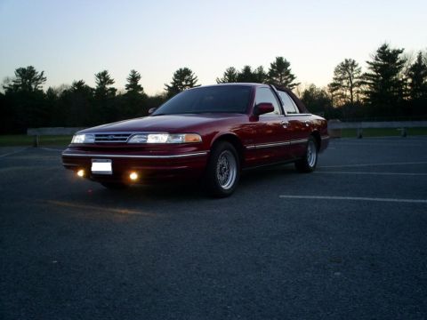 1995 Ford Crown Victoria - A maroon 1995 Ford Crown Victoria is parked in an empty lot as the sun sets.