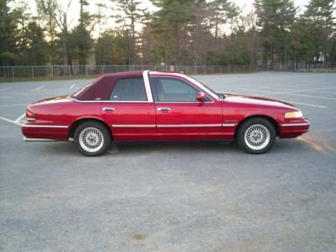 1995 Ford Crown Victoria - Side view of a red 1995 Ford Crown Victoria sedan a maroon vinyl roof.