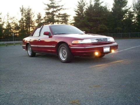 1995 Ford Crown Victoria - A red 1995 Ford Crown Victoria is shown from the front quarter angle in a parking lot.