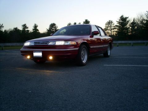 1995 Ford Crown Victoria - A red 1995 Ford Crown Victoria is parked in a lot at dusk.