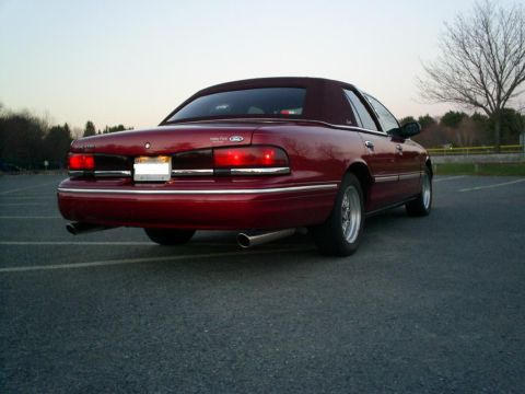 1995 Ford Crown Victoria - This red 1995 Ford Crown Victoria convertible sedan is viewed from the rear, showing its dual exhaust and chrome accents.