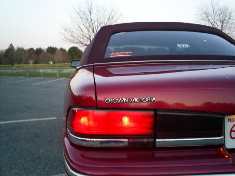 1995 Ford Crown Victoria - Rear view of a red 1995 Ford Crown Victoria convertible with its taillights illuminated.