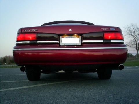 1995 Ford Crown Victoria - Rear view of a red 1995 Ford Crown Victoria, its distinctive taillights and chrome trim. The license plate frame indicates 'Valley Ford'.