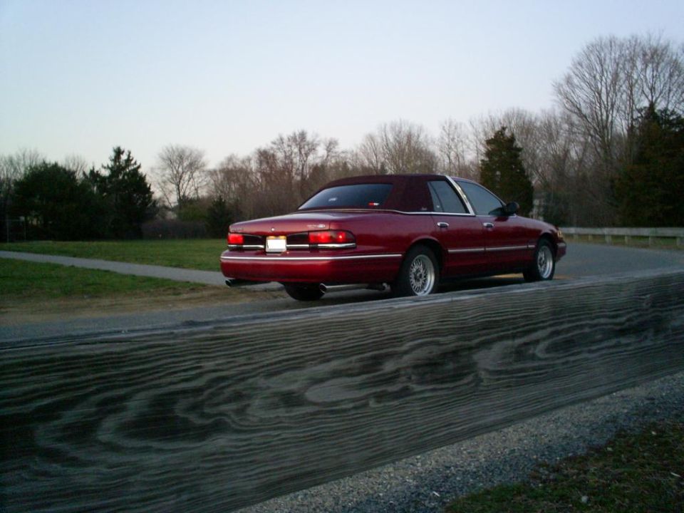 Red sedan with a vinyl top driving on a road