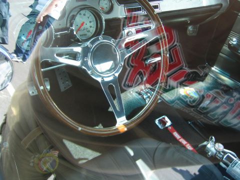 1968 Ford Mustang - The interior of a 1968 Ford Mustang shows a wood-rimmed steering wheel, a prominent RPM gauge, and custom graphics on the dashboard.
