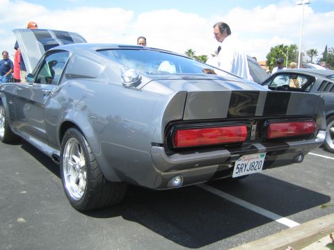 1968 Ford Mustang - A gray 1968 Ford Mustang Shelby GT500 is seen from the rear at a car show, black racing stripes and a California license plate.