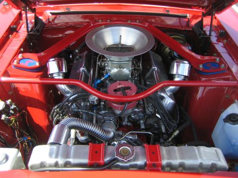 1968 Ford Mustang - The engine bay of a classic car features a V8 engine with chrome accents and a prominent air intake system.