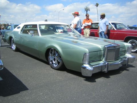 1968 Ford Mustang - A classic Lincoln Continental is displayed at an outdoor car show with other vehicles present.