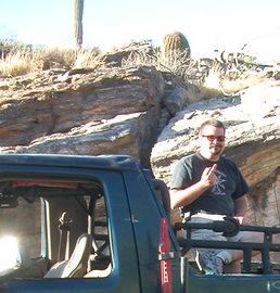 1990 Ford Bronco - A man poses for a photo from inside an off-road vehicle, with a desert landscape behind him.