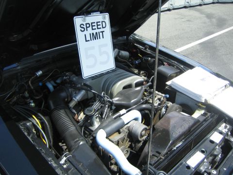 1968 Ford Mustang - Car engine bay displayed with a speed limit sign, likely at a car show.