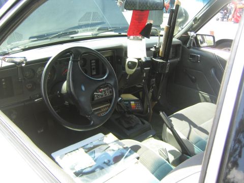 1968 Ford Mustang - Interior view of a car equipped with a police radio and a mounted shotgun.