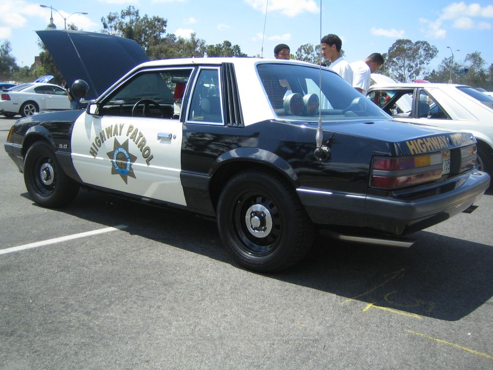 Black and white police car with hood open, side view