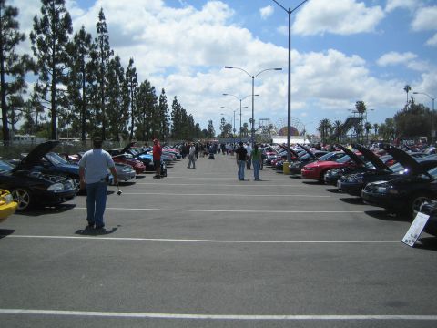 1968 Ford Mustang - A car show features many vehicles with their hoods open, parked in rows under a partly cloudy sky.