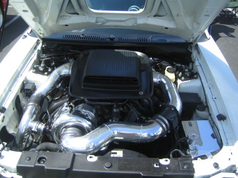 1968 Ford Mustang - Customized engine bay a large turbocharger and polished intake system, likely a modern Mustang variant.