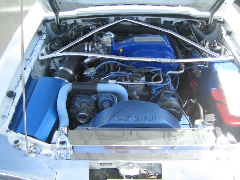 1968 Ford Mustang - Customized engine bay a blue Saleen intake manifold and a prominent blue fan shroud with 'CAUTION FAN' text.