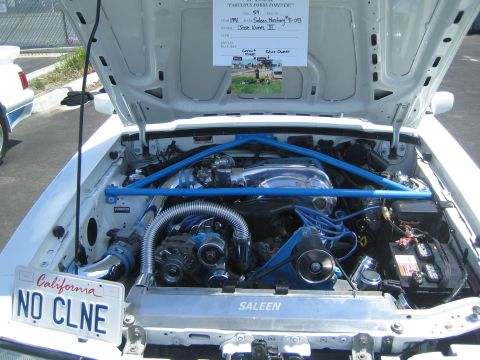1968 Ford Mustang - The engine bay of a modified Ford Mustang, a prominent blue strut tower brace and custom Saleen badging.
