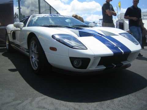 1968 Ford Mustang - A white Ford GT with blue racing stripes is parked on asphalt under a cloudy sky.