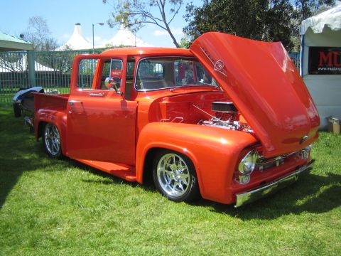 1968 Ford Mustang - A bright orange pickup truck is parked on a grassy lawn with its hood and driver's door open.