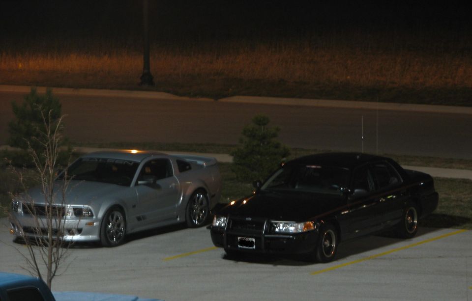 Silver Ford Mustang and black Ford Crown Victoria parked at night