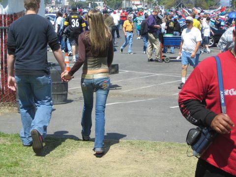 1968 Ford Mustang - A couple walks through a crowded outdoor event with numerous vehicles and attendees visible in the background.