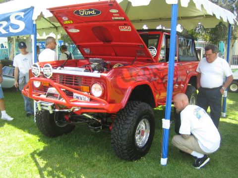 1968 Ford Mustang - A customized red Ford Bronco with flame graphics is displayed with its hood open, revealing the engine bay.