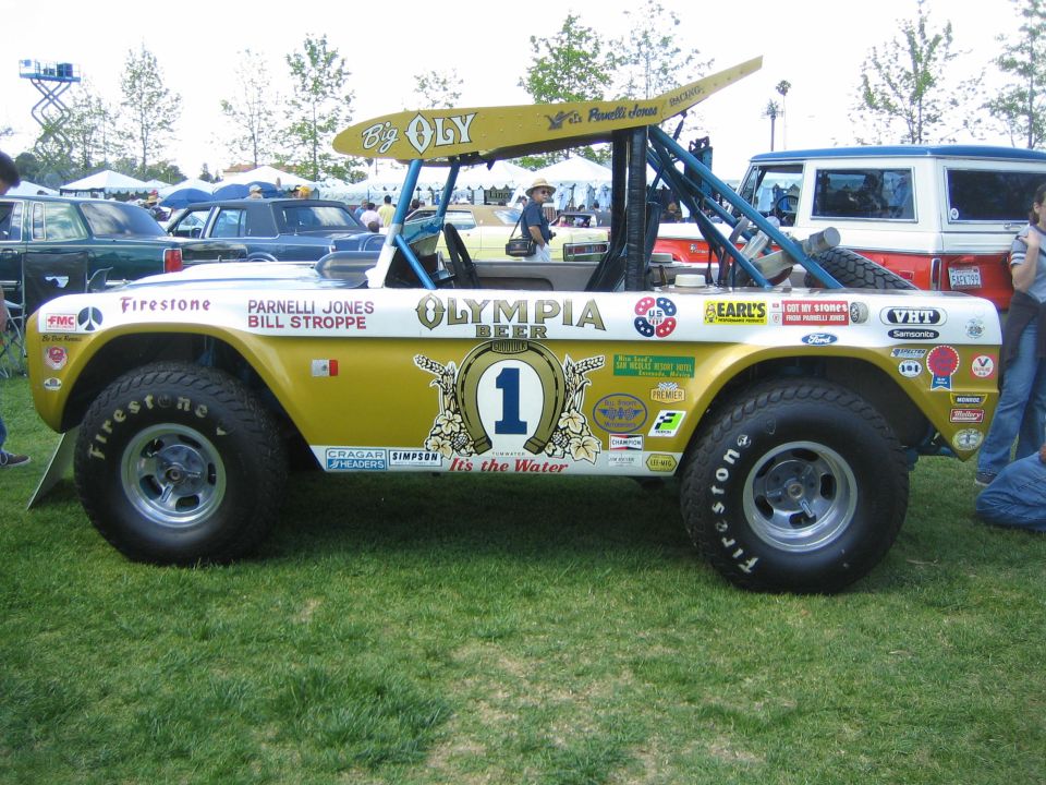 Off-road vehicle with gold and white paint, "Big Oly" text on roof, and numerous sponsor decals