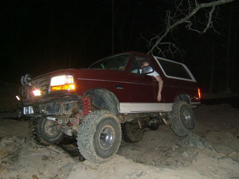 1993 Ford Bronco - A lifted 1993 Ford Bronco navigates a rocky trail in the dark.
