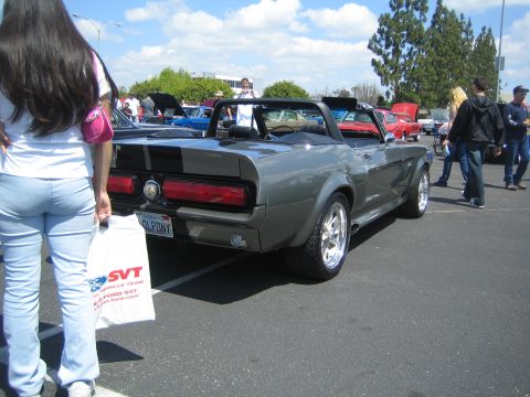 1968 Ford Mustang - A gray 1968 Ford Mustang convertible with black racing stripes is parked at a car show.