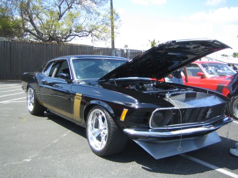 1968 Ford Mustang - A black 1970 Ford Mustang Boss 302 is displayed with its hood up, parked next to a red car.