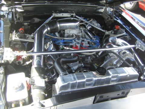 1968 Ford Mustang - The engine bay of a 1968 Ford Mustang shows a V8 engine with chrome accents and blue spark plug wires.
