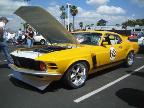 1968 Ford Mustang - A yellow 1970 Ford Mustang Boss 302 is displayed with its hood open at an outdoor car show.