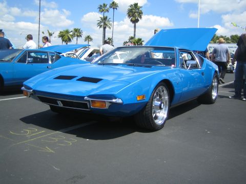 1968 Ford Mustang - A bright blue De Tomaso Pantera is displayed with its hood open at an outdoor car show.
