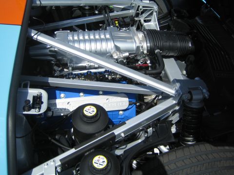 1968 Ford Mustang - The engine bay reveals a powerful V8 with a prominent supercharger and blue Ford branding on the valve covers.