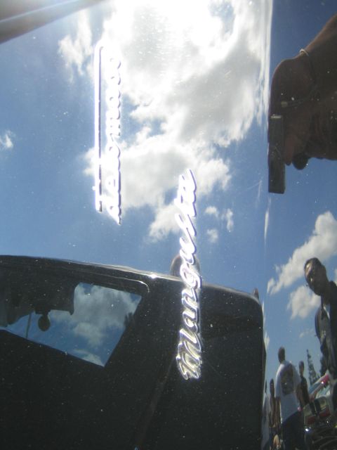 1968 Ford Mustang - Chrome lettering on a black car reflects the sky and onlookers, indicating it is a Maserati, not a 1968 Ford Mustang.