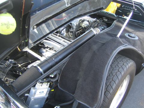 1968 Ford Mustang - The engine bay of a car is shown with the hood open. A tennis ball rests on the left side.